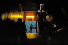 two people are walking up the stairs at night in front of an open door to another room