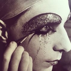 a black and white photo of a woman with glitter on her face