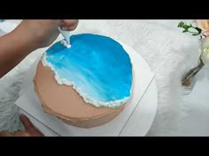 a person is cutting into a cake with blue frosting on the top and bottom