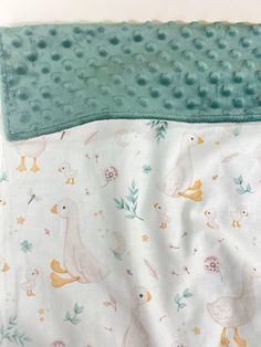 two baby blankets with ducks and flowers on them, one is green and the other is white