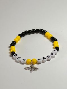 "This is a super cute and inspirational handmade beaded bracelet. Very pretty black and yellow color with the words \"Bee Happy\" beads and a little Bee charm for accent on a stretchy elastic. Would fit a 6.5\" wrist and possibly 7\".   The words really make the bracelet a reminder that you or whoever you gift it to should always be happy!! Picture taken in different lighting to show how it looks under different settings. We offer free shipping on all of our items! If you are interested in a cer Bee Charm For Bracelet, Playful Black Beaded Bracelets With Letter Beads, Fun Black Beaded Bracelets With Round Beads, Personalized Yellow Stretch Bracelet As Gift, Cute Black Beaded Bracelets For Birthday, Fun Personalized Black Bracelets, Personalized Fun Black Beaded Bracelets, Handmade Fun Black Beaded Bracelets, Fun Handmade Black Beaded Bracelets