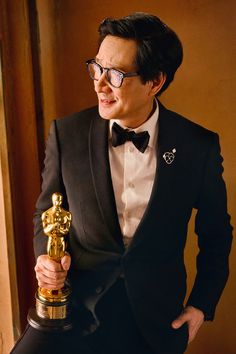 a man in a tuxedo holding an oscar statue