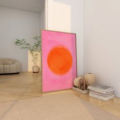 there is a pink and orange painting on the wall next to a pile of books