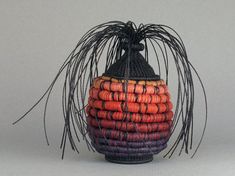 a decorative vase made out of woven material with black and orange stripes on it's sides