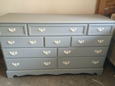 a gray dresser with white knobs on it's drawers and the top drawer is missing