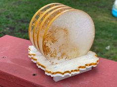 a stack of yellow and white plates sitting on top of a red table next to a green field