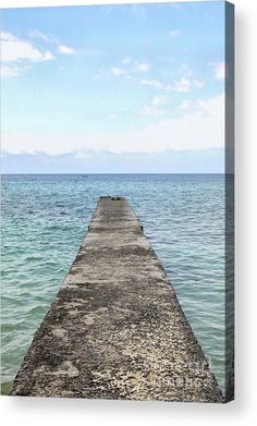 a long pier stretching out into the ocean with blue sky and clouds in the background