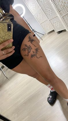 a woman with tattoos on her leg holding a cell phone