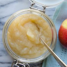 an apple pie in a glass jar with a spoon next to it