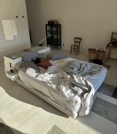 a person laying on top of a bed in a room with white walls and flooring