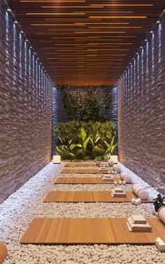 a long row of wooden benches sitting next to each other in front of a stone wall