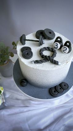 a white cake with black buttons on it and some flowers in the backround