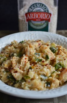 a white bowl filled with rice and vegetables next to a bottle of arrojo