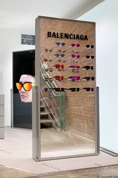 a display case with sunglasses on it in front of a brick wall that says balenocia