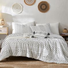 a bed with white and black bedspread in front of two wall hangings