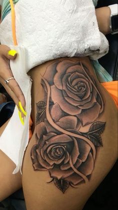 a close up of a person's stomach with tattoos on her legs and roses