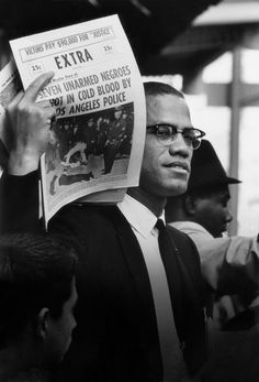 black and white photograph of man holding up newspaper with extra written on it in front of other men