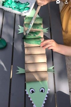 a child is making a paper alligator craft