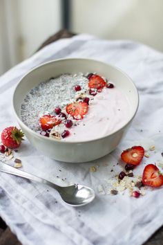 a bowl of oatmeal with strawberries and granola on the side