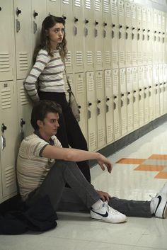 two people sitting on the floor in front of lockers