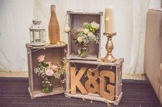 three wooden crates with flowers and letters on them are sitting next to a lit candle