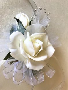 a white rose is in a clear glass vase with pearls on the rim and beading around it