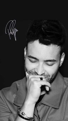 a black and white photo of a man holding his hand to his face while looking down