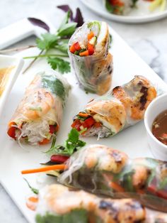 several different types of food on a white plate with dipping sauce and chopsticks