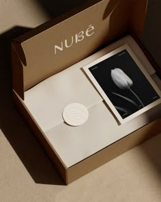 an open box with a white flower in it's center and the word nuse on top