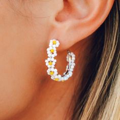 a close up of a woman's ear wearing white and yellow flowers on it