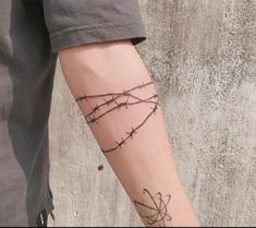 a person with a tattoo on their arm holding a cell phone and barbed wire behind them