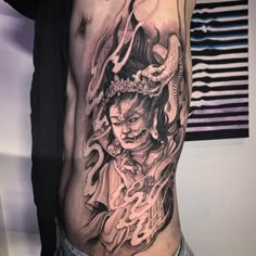 a man with a tattoo on his stomach has a dragon and demon design on it