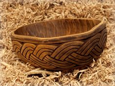 a wooden bowl sitting on top of wood shavings in a pile of straw