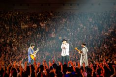 the rolling stones performing on stage in front of a large crowd with their hands up