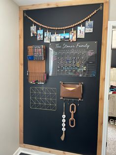 a chalkboard with pictures and magnets on it next to a purse hanging from the wall