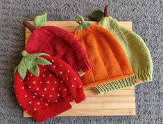 three knitted hats sitting on top of a cutting board