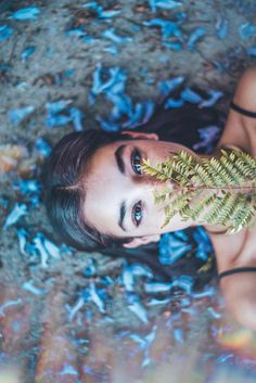 a woman is laying on the ground with a plant in her hand and looking up at the camera