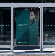 an advertisement on the side of a building in front of a glass door with a man's face