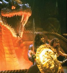 an image of two women in front of a giant snake and another woman holding a shield