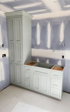 an unfinished kitchen with white cabinets and blue walls