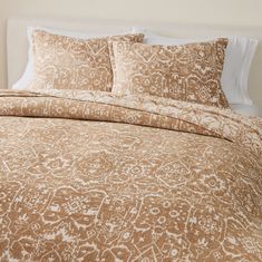 a bed with a brown and white comforter on top of it