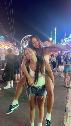 two girls are posing for the camera at an amusement park