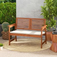 a wooden bench sitting on top of a rug next to a potted cactus plant