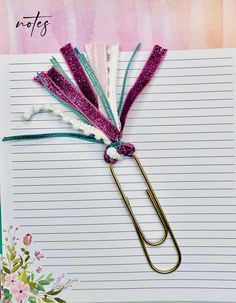 an open notebook with paper clips attached to it and flowers on the page next to it