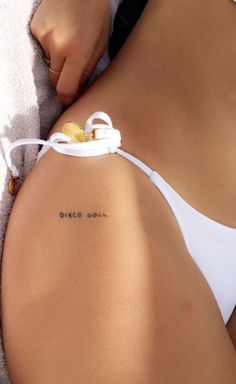 a woman laying on the beach with her back to the camera and tattoos on her chest