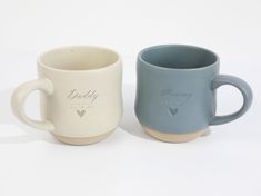 two coffee mugs sitting next to each other on a white surface with the words daddy and mommy printed on them