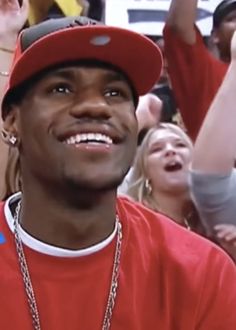 a young man wearing a red hat and holding his hands up in front of him