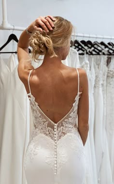 the back of a woman's wedding dress in front of a rack of dresses