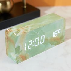 an alarm clock sitting on top of a marble counter next to a vase and lamp