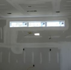 an unfinished room with white walls and two windows